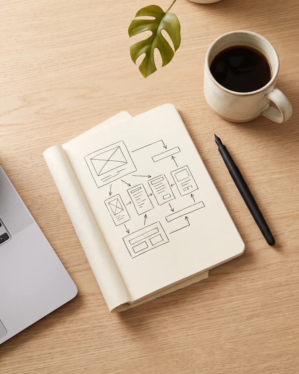 Notebook with a hand-drawn software architecture sketch on an oak desk